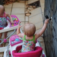 Becca has learned how to turn on the spicket and spray Anna. Becca has learned how to turn on the spicket and spray Anna.
